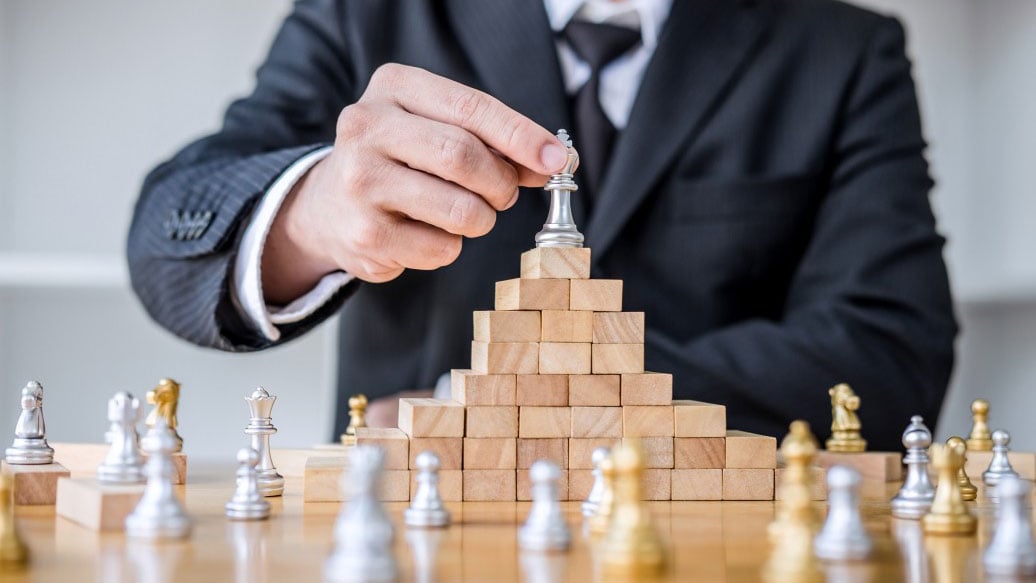 wooden-game-of-strategy-hands-of-confident-businessman-playing-chess-game-to-development-analysis-new_t20_E4RYXQ